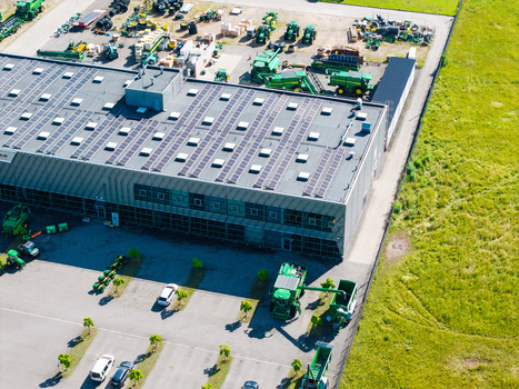 Kekava Latvia 05 July 2026 Aerial view of an agricultural machinery dealership featuring a large warehouse with solar panels on the roof surrounded by parked tractors and farm equipment in a rural setting. Kekava Latvia 05 July 2026 Aerial view of an agricultural machinery dealership featuring a large warehouse with solar panels on the roof surrounded by parked tractors and farm equipment in a rural setting.