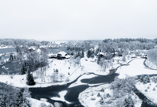 Aerial view of a serene winter landscape featuring frozen ponds snow covered pine trees and traditional houses nestled in the countryside Latvia. Aerial view of a serene winter landscape featuring frozen ponds snow covered pine trees and traditional houses nestled in the countryside Latvia.