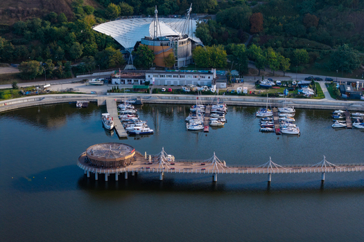 Aerial view of the modern pier and marina on the Vistula River featuring docked sailboats a circular wooden structure and the amphitheater in Plock Masovian Voivodeship Poland.