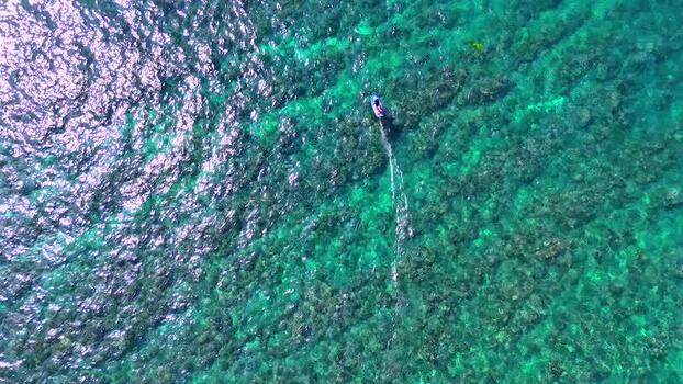 Aerial view of a man riding an e foil over a reef and blue water United States.United States. Aerial view of a man riding an e foil over a reef and blue water United States.United States.