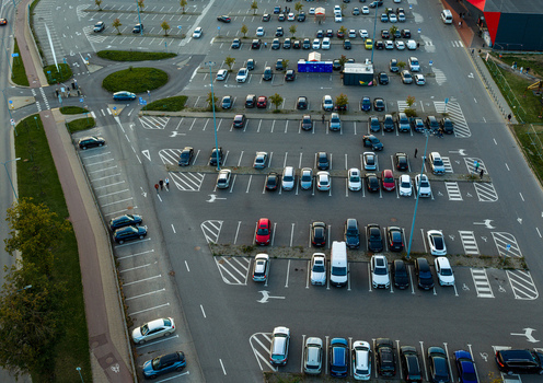 Aerial view of a large parking lot with numerous cars parked in marked spaces surrounded by green areas and roads in Vilnius Vilnius County Lithuania. Aerial view of a large parking lot with numerous cars parked in marked spaces surrounded by green areas and roads in Vilnius Vilnius County Lithuania.