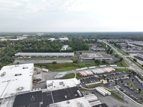 Aerial view of a large industrial warehouse complex with semi truck trailers parked in the lot a small pond and surrounding green space in Indianapolis Indiana United States. Aerial view of a large industrial warehouse complex with semi truck trailers parked in the lot a small pond and surrounding green space in Indianapolis Indiana United States.