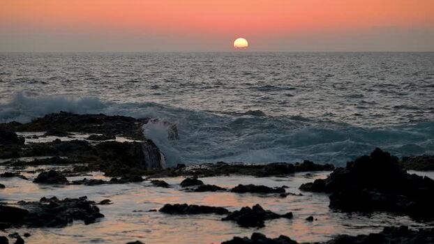 View of sunset over ocean with crashing waves United States.