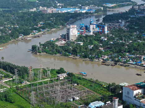 Aerial view of the Karnaphuli River winding through industrial facilities and lush greenery in Chattogram Chattogram Division Bangladesh.
