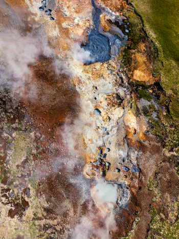 Aerial view of steaming geothermal vents bubbling mud pools and vibrant mineral deposits in the volcanic landscape of Iceland. Aerial view of steaming geothermal vents bubbling mud pools and vibrant mineral deposits in the volcanic landscape of Iceland.