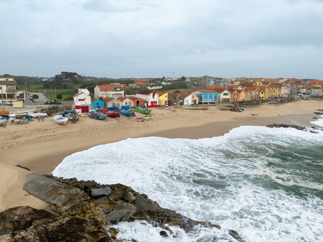 Aerial view of vibrant colorful houses stand boldly against the serene sandy beach where fishing boats rest and waves crash Vila Chã Porto Portugal. Aerial view of vibrant colorful houses stand boldly against the serene sandy beach where fishing boats rest and waves crash Vila Chã Porto Portugal.