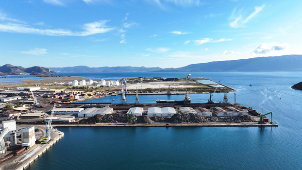 Aerial view of the Port of Ploce featuring industrial cranes storage tanks and warehouses along the coastline with mountains in the background in Croatia.