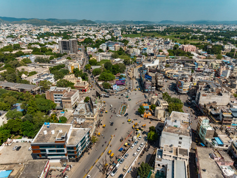 Aerial view of the bustling urban landscape of Udaipur with dense buildings busy streets and surrounding greenery in Udaipur Rajasthan India.