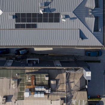 Aerial view of a metal roof with solar panels installed adjacent to a flat roof with HVAC units and parked cars in Istanbul Istanbul Turkiye.