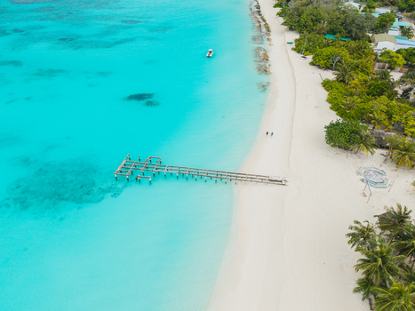 Aerial view of turquoise waters meet the pristine white sands of the beach contrasting with the lush greenery Vashafaru Island Thiladhummathi Atoll Maldives. Aerial view of turquoise waters meet the pristine white sands of the beach contrasting with the lush greenery Vashafaru Island Thiladhummathi Atoll Maldives.