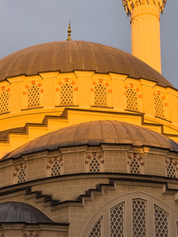 View of the golden domes and minaret of a mosque during sunset with intricate window details in Avcilar Istanbul Turkey. View of the golden domes and minaret of a mosque during sunset with intricate window details in Avcilar Istanbul Turkey.