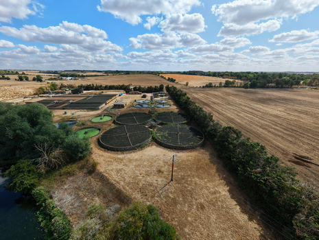 Aerial view of a wastewater treatment works featuring circular sedimentation tanks surrounded by rural fields and trees in St Neots England United Kingdom. Aerial view of a wastewater treatment works featuring circular sedimentation tanks surrounded by rural fields and trees in St Neots England United Kingdom.