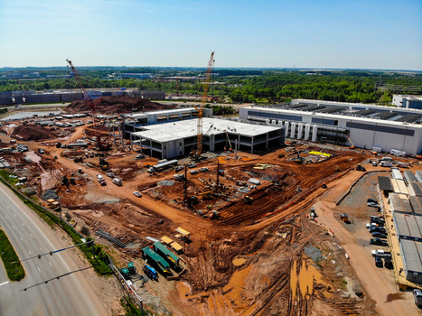 Aerial view of a large construction site featuring cranes heavy machinery and a building structure under development in Ashburn Virginia United States. Aerial view of a large construction site featuring cranes heavy machinery and a building structure under development in Ashburn Virginia United States.