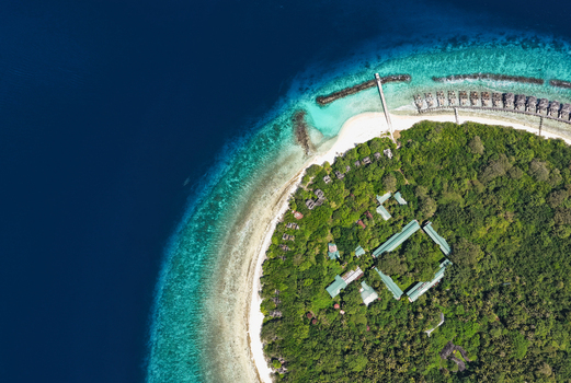 Aerial view of an abandoned island resort with lush green vegetation white sandy beaches and turquoise coral reefs surrounded by deep blue ocean waters in Muraidhoo Haa Alif Atoll Maldives. Aerial view of an abandoned island resort with lush green vegetation white sandy beaches and turquoise coral reefs surrounded by deep blue ocean waters in Muraidhoo Haa Alif Atoll Maldives.