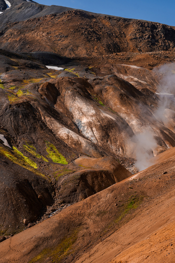 View of geothermal landscape with vibrant green moss contrasting against the dark textured earth and rising steam in Iceland s rugged terrain Hrunamannahreppur Iceland.