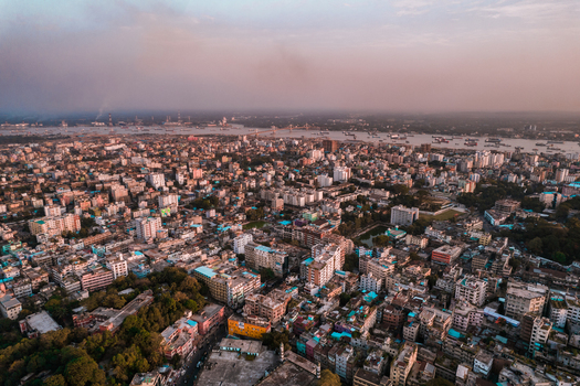 Chattogram Bangladesh 25 February 2022 Aerial view of the dense urban cityscape of Chattogram featuring a sprawling network of buildings lush green patches and the river in the distance.