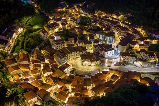 Aerial view of the illuminated historic town of Cudillero at night with its characteristic red tiled rooftops and glowing streets nestled in the hills Cudillero Asturias Spain. Aerial view of the illuminated historic town of Cudillero at night with its characteristic red tiled rooftops and glowing streets nestled in the hills Cudillero Asturias Spain.