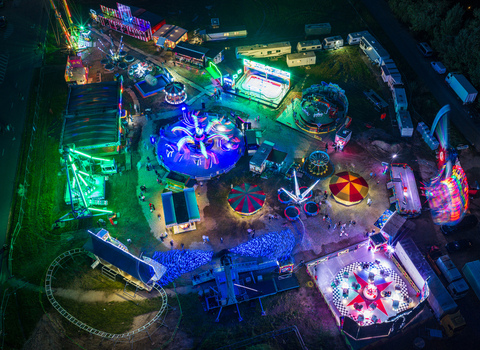 Aerial view of a vibrant fairground at night with illuminated spinning rides colorful lights and parked trailers in Vilnius Vilnius County Lithuania. Aerial view of a vibrant fairground at night with illuminated spinning rides colorful lights and parked trailers in Vilnius Vilnius County Lithuania.