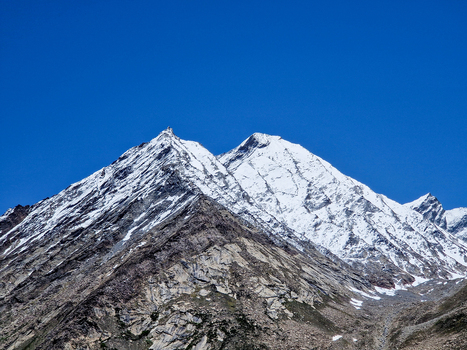 View of the snow capped mountain peaks near Penzi La road with rugged rocky slopes and a clear blue sky in Zanskar Ladakh India.