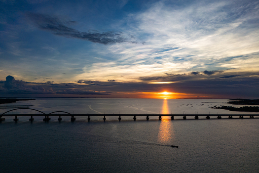 Aerial view of Bintan Island with a long arched bridge spanning the sea during a vibrant sunset with golden light reflecting on the water Tanjung Pinang Riau Islands Indonesia. Aerial view of Bintan Island with a long arched bridge spanning the sea during a vibrant sunset with golden light reflecting on the water Tanjung Pinang Riau Islands Indonesia.