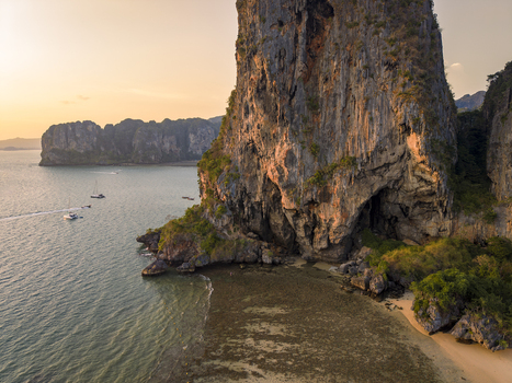Aerial view of towering limestone cliffs meet the turquoise sea in a symphony of light and shadow Railay Beach Thailand.