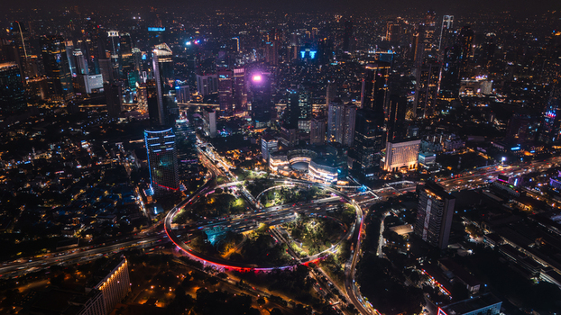 Aerial view of the illuminated Semanggi Interchange surrounded by skyscrapers and city lights at night in Jakarta Indonesia.