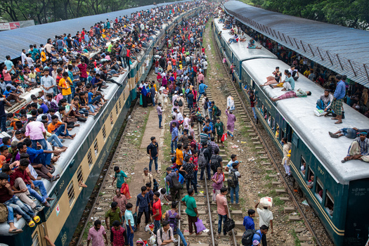 Dhaka Bangladesh 15 June 2018 View of Airport Railway Station crowded with people sitting on train roofs and walking along the tracks during Eid al Fitr rush. Dhaka Bangladesh 15 June 2018 View of Airport Railway Station crowded with people sitting on train roofs and walking along the tracks during Eid al Fitr rush.