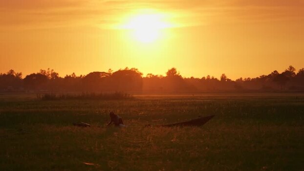 View of a fisherman with a boat at sunset in Bogura Bangladesh. View of a fisherman with a boat at sunset in Bogura Bangladesh.