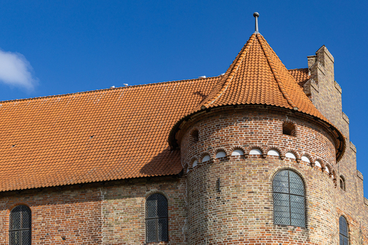 View of the historic brick architecture and red tiled roof of Nyborg Castle under a clear blue sky in Nyborg Fyn Denmark. View of the historic brick architecture and red tiled roof of Nyborg Castle under a clear blue sky in Nyborg Fyn Denmark.