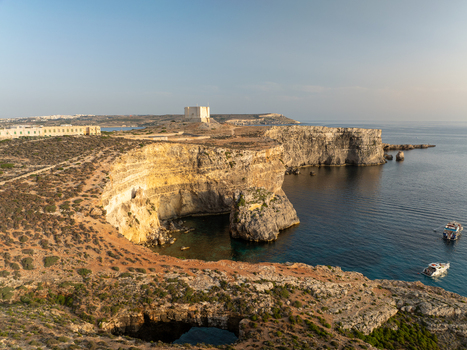 Aerial view of rugged cliffs meet the turquoise sea near the iconic Blue Lagoon a paradise of contrasting colors and textures Comino Malta. Aerial view of rugged cliffs meet the turquoise sea near the iconic Blue Lagoon a paradise of contrasting colors and textures Comino Malta.
