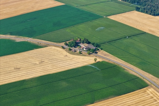 Aerial view of a farmstead surrounded by lush green and golden agricultural fields with irrigation systems in Hombourg Grand Est France. Aerial view of a farmstead surrounded by lush green and golden agricultural fields with irrigation systems in Hombourg Grand Est France.