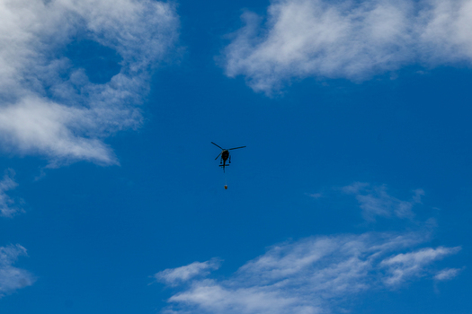 View of a helicopter flying through a bright blue sky with scattered white clouds over Ghakhar Gilgit Pakistan. View of a helicopter flying through a bright blue sky with scattered white clouds over Ghakhar Gilgit Pakistan.