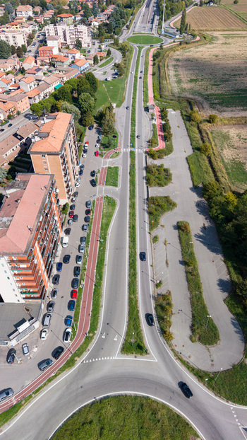 Aerial view of a provincial road with a roundabout red bike path and parked cars alongside residential buildings in Cremona Lombardia Italy.