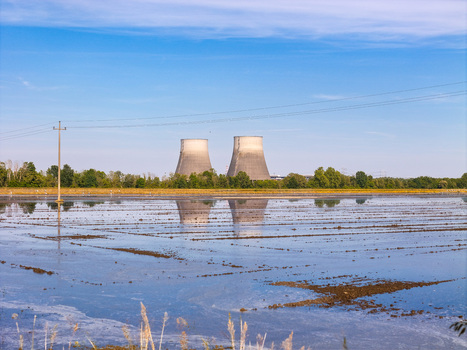 Aerial view of cooling towers of a power plant reflecting in flooded rice paddies under a clear blue sky Livorno Ferraris Piemonte Italy.