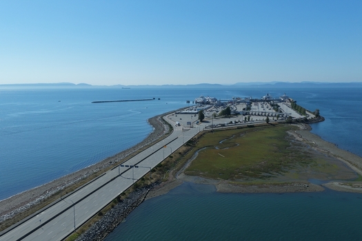 Aerial view of the BC Ferries Tsawwassen Ferry Terminal featuring the toll booths ferry docks and expansive coastal waters under a clear blue sky in Delta British Columbia Canada. Aerial view of the BC Ferries Tsawwassen Ferry Terminal featuring the toll booths ferry docks and expansive coastal waters under a clear blue sky in Delta British Columbia Canada.