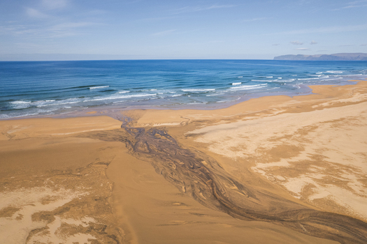 Aerial view of the golden sands of Raudisandur beach with a river delta flowing into the blue ocean waves in Vesturbyggd Iceland. Aerial view of the golden sands of Raudisandur beach with a river delta flowing into the blue ocean waves in Vesturbyggd Iceland.