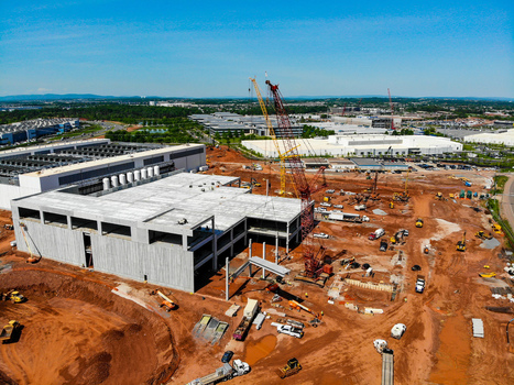 Aerial view of a large construction site with concrete structures tall cranes and heavy machinery on red earth in Ashburn Virginia United States. Aerial view of a large construction site with concrete structures tall cranes and heavy machinery on red earth in Ashburn Virginia United States.