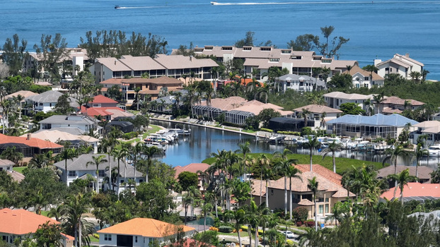 Aerial view of the coastal residential community of Cortez featuring houses with boat docks along canals surrounded by palm trees with open water. Cortez Florida United States.