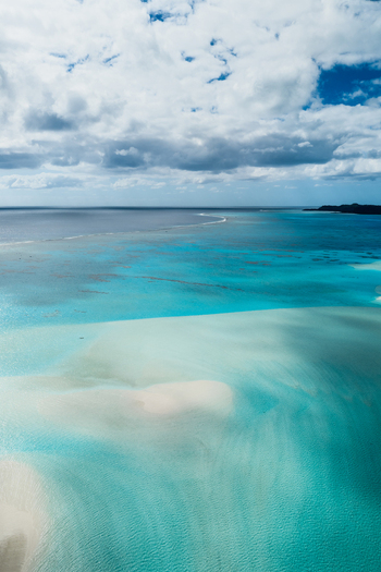 Aerial view of Aitutaki lagoon with turquoise water sandbars and clouds in Cook Islands. Aerial view of Aitutaki lagoon with turquoise water sandbars and clouds in Cook Islands.