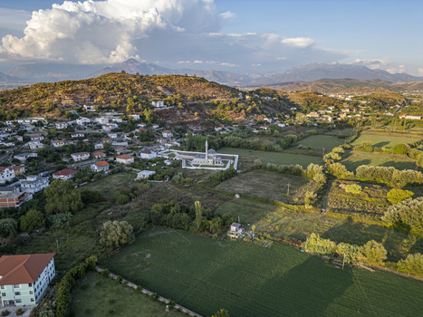 Aerial view of the Lead Mosque surrounded by green fields scattered houses and rolling hills under a cloudy sky in Shkoder Shkoder County Albania. Aerial view of the Lead Mosque surrounded by green fields scattered houses and rolling hills under a cloudy sky in Shkoder Shkoder County Albania.