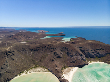Aerial view of Balandra beach with turquoise waters white sand and surrounding arid hills under a clear blue sky in La Paz Baja California Sur Mexico. Aerial view of Balandra beach with turquoise waters white sand and surrounding arid hills under a clear blue sky in La Paz Baja California Sur Mexico.