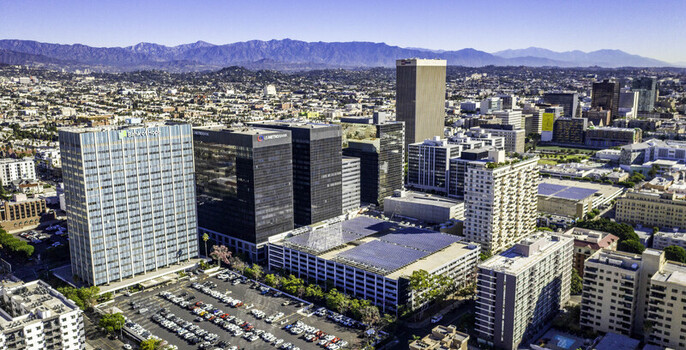 Los Angeles California United States 19 October 2018 Aerial view of a building with a solar panel array on its roof surrounded by urban architecture and parking lots. Los Angeles California United States 19 October 2018 Aerial view of a building with a solar panel array on its roof surrounded by urban architecture and parking lots.