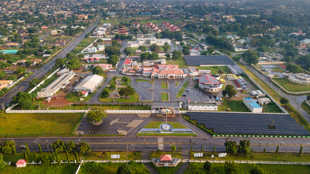 Aerial view of the Niger State Government House complex featuring administrative buildings parking areas and solar panel arrays surrounded by lush greenery in Minna Niger Nigeria. Aerial view of the Niger State Government House complex featuring administrative buildings parking areas and solar panel arrays surrounded by lush greenery in Minna Niger Nigeria.
