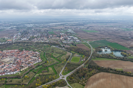 Aerial view of the star shaped fortress with its red tiled rooftops and geometric fortifications contrasting against the surrounding green fields Neuf Brisach Grand Est France.