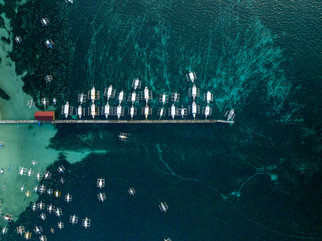 Aerial view of traditional outrigger boats moored along a long pier in the turquoise waters of Naked Island Siargao Philippines. Aerial view of traditional outrigger boats moored along a long pier in the turquoise waters of Naked Island Siargao Philippines.