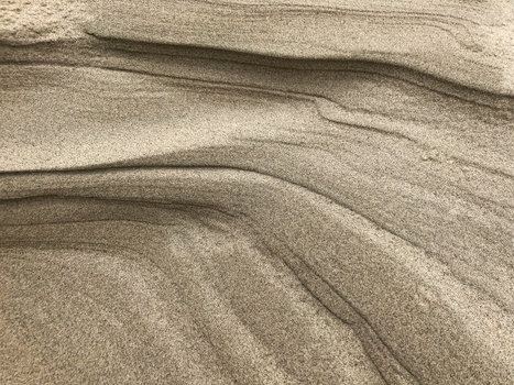 View of layers of sand sculpted by wind and water creating a textured landscape of natural patterns and subtle color variations De Cocksdorp Noord Holland Netherlands. View of layers of sand sculpted by wind and water creating a textured landscape of natural patterns and subtle color variations De Cocksdorp Noord Holland Netherlands.