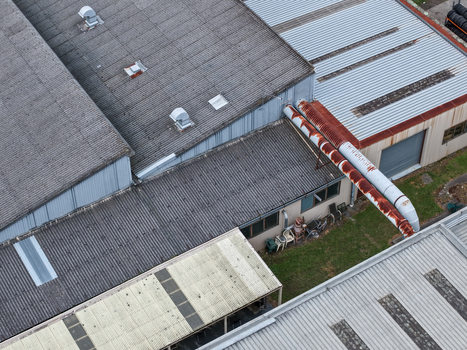 Aerial view of industrial factory rooftops with corrugated metal surfaces rusty ventilation pipes and small outdoor area in Melbourne VIC Australia.