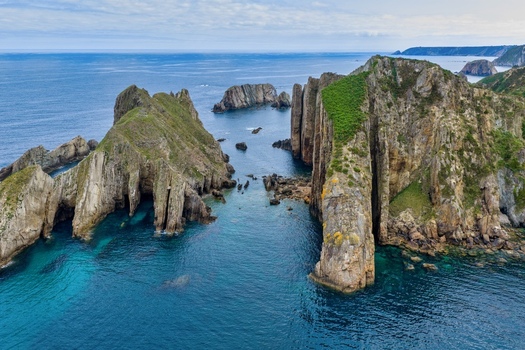 Aerial view of Silence Beach Viewpoint with dramatic jagged cliffs turquoise ocean water and rocky islets in Cudillero Asturias Spain.