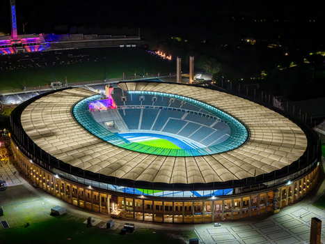 Berlin Germany 26 September 2026 Aerial view of Olympiastadion Berlin illuminated at night with its distinctive roof structure and green pitch visible.