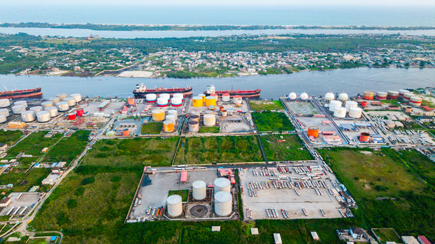 Aerial view of the industrial oil and gas storage facility in Satellite Town with large storage tanks parked tanker trucks and ships docked along the river in Lagos Lagos Nigeria.